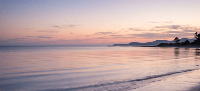 Calm sea with gentle waves at sunset along a sandy beach